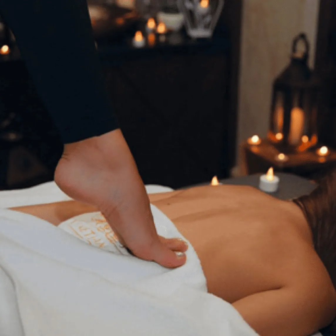 Therapist's foot pressing into a guest's back during a Thai Tranquility Therapy session
